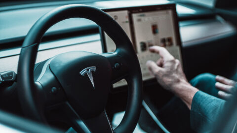 Person in Tesla interacting with large touch screen.
