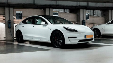 White Tesla car parked in parking garage and charging.